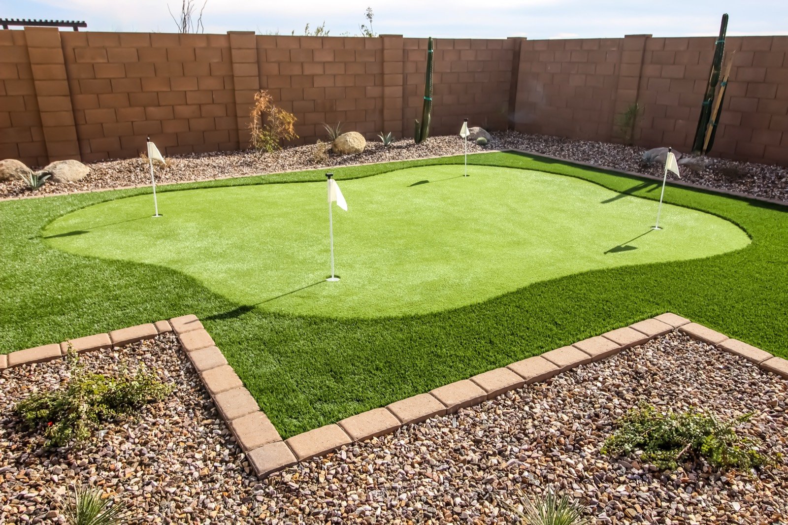 Residential backyard putting green with four holes and brick edging