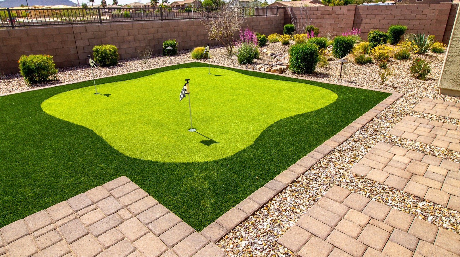 Custom putting green in a residential rear yard with paver patio